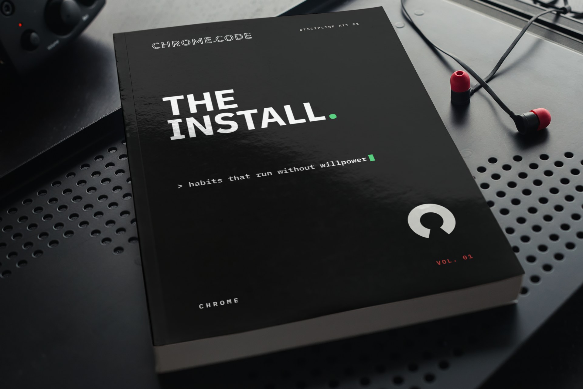 THE INSTALL paperback on a dark desk next to red earbuds